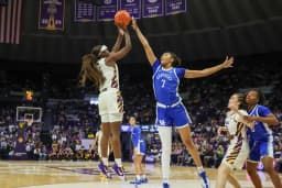 A Kentucky player rises for a contested jump shot as an LSU defender challenges during a women’s college basketball game.
