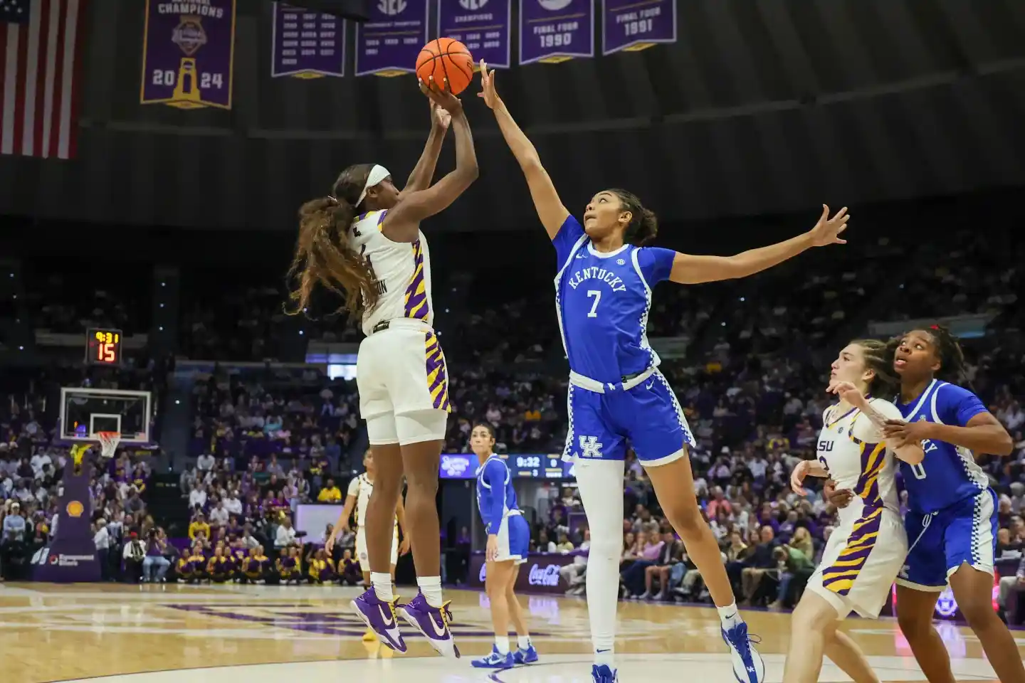 A Kentucky player rises for a contested jump shot as an LSU defender challenges during a women’s college basketball game.