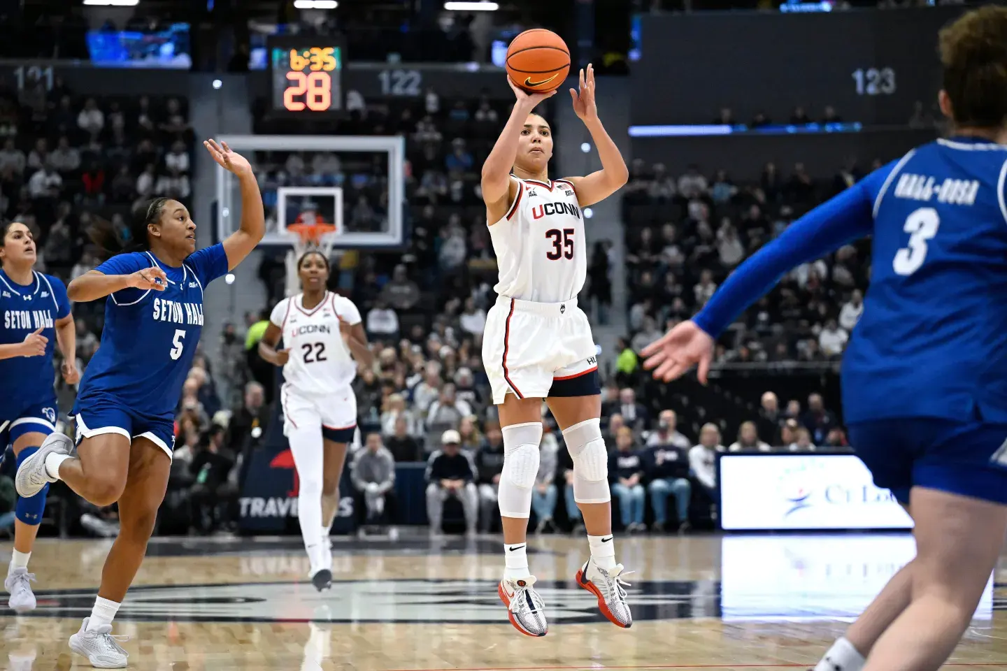 A UConn player pulls up for a jump shot against Seton Hall defenders in Big East action.