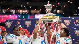 Ole Miss Rebels players lift the Sugar Bowl championship trophy amid falling confetti after defeating Georgia in the College Football Playoff quarterfinal