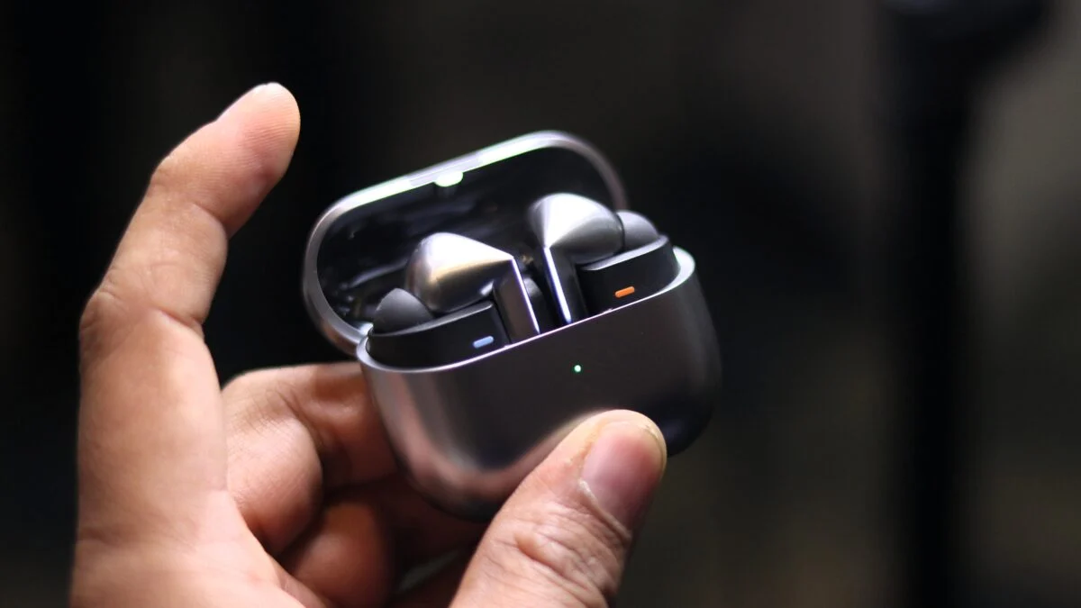 Person holding Samsung Galaxy Buds 4 and Buds 4 Pro in a charging case.