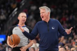 A basketball coach argues with a referee while gesturing during an NBA game.