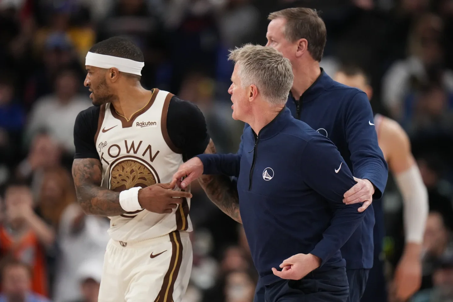 A coach is restrained by staff while speaking to a player during a heated moment on the court.