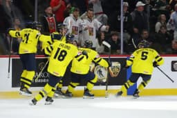 Swedish players celebrate a goal together along the boards during the World Junior Championship final.