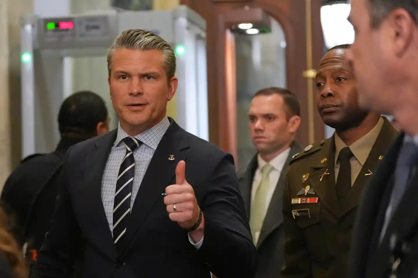 A U.S. official gives a thumbs-up while speaking with reporters inside the Capitol.