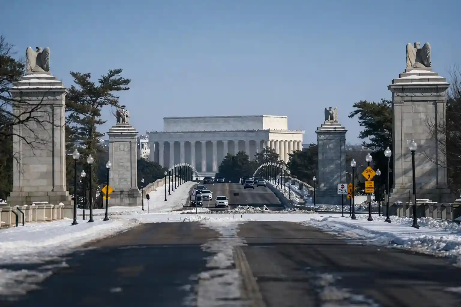 View of the Lincoln Memorial in Washington, D.C., with snow-covered roads and sculptures of eagles flanking the entrance.