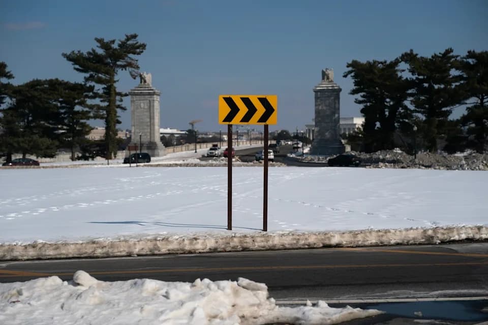 Snowy streets near the Lincoln Memorial in Washington, D.C., showing a warning traffic sign about a curve