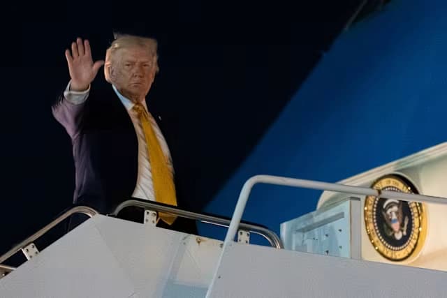 President Donald Trump waves while boarding Air Force One during an overnight departure