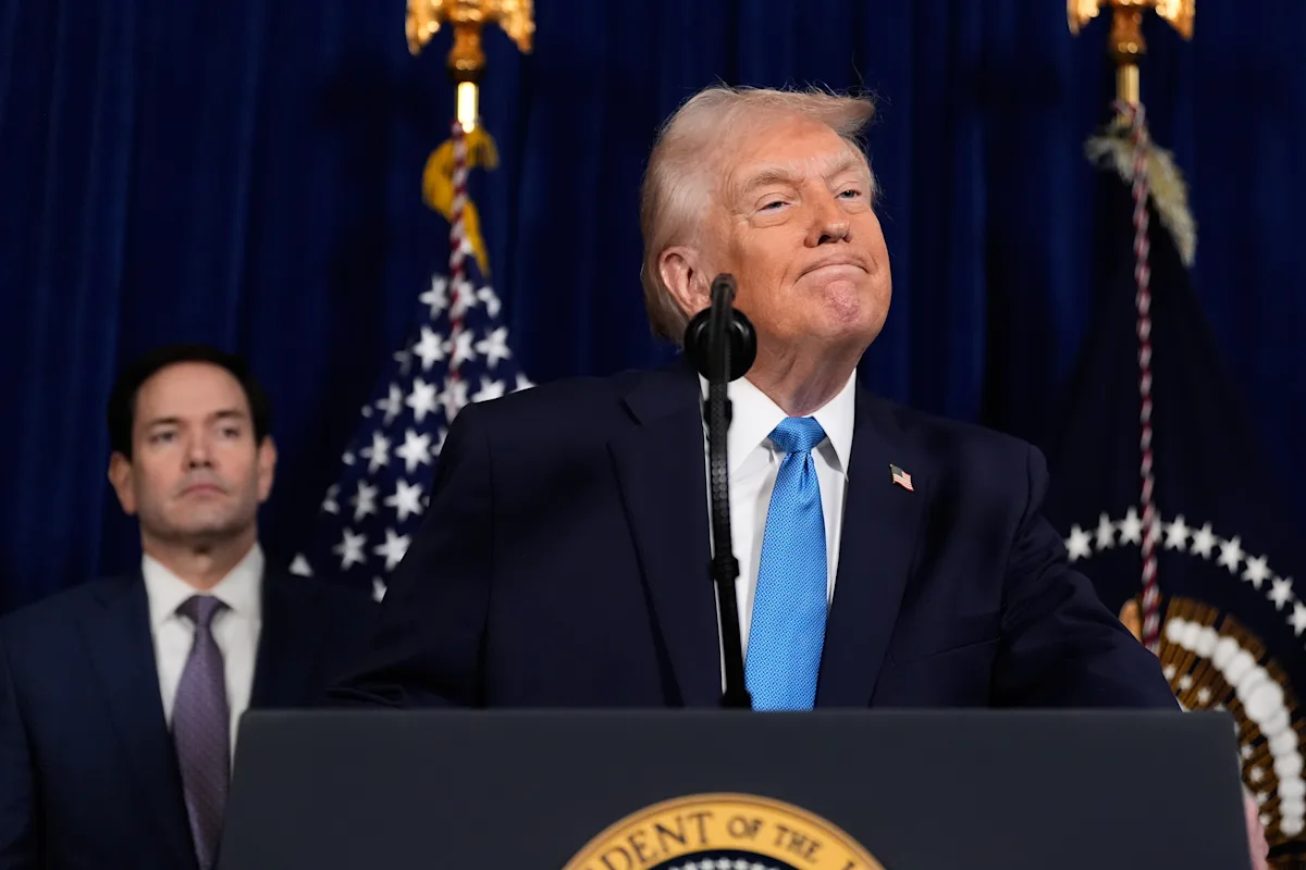 President Donald Trump pauses at the podium with U.S. flags in the background during remarks
