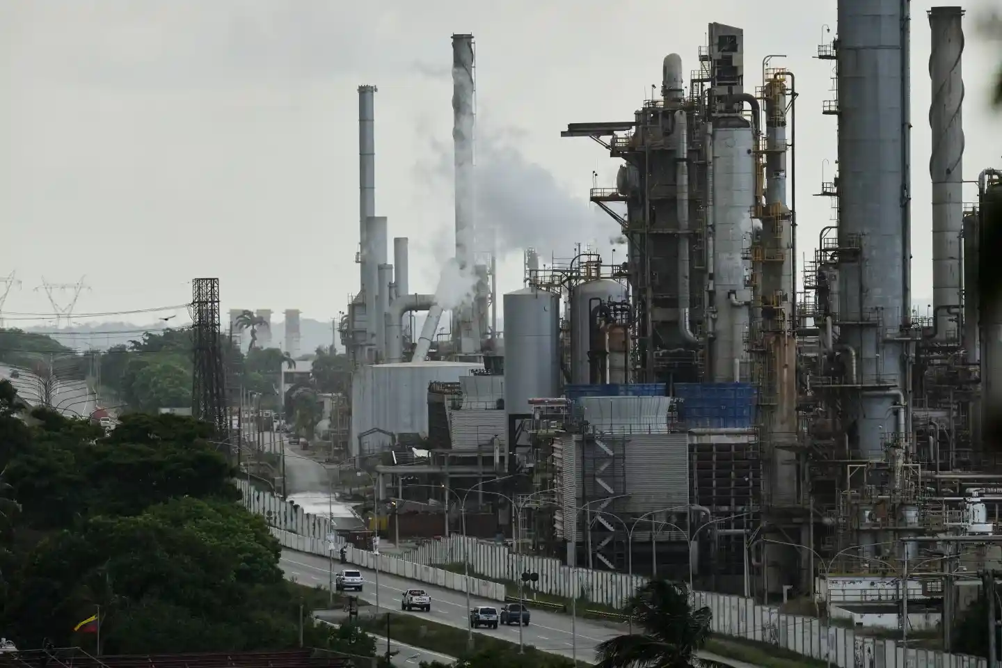 Industrial oil refinery complex in Venezuela with smokestacks and processing towers along a roadway