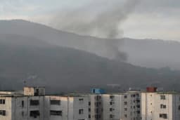 Smoke rises over a residential area near hills as unrest unfolds following the U.S. operation in Venezuela
