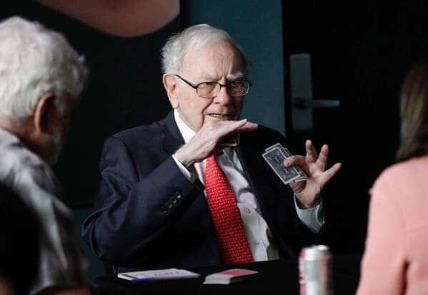 Warren Buffett speaking while playing cards at a meeting